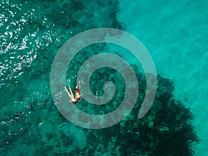 Snorkeling couple in the middle of the Indian Ocean, coral reefs, green water, from high above. Birds eye view.