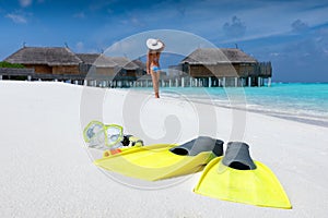 Snorkeling gear on a tropical beach with woman walking on the beach