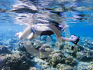 Snorkeling girl with underwater camera in coral reef. Snorkel with camera in underwater housing.