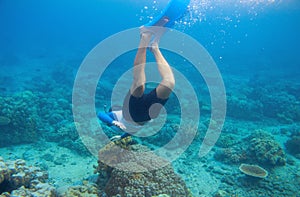 Snorkeling man dives to coral reef. Male snorkel in tropical lagoon underwater photo