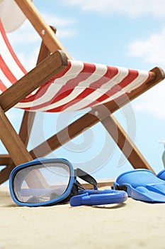 Snorkeling mask and flippers under deckchair on beach