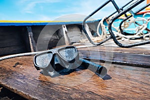 Snorkeling mask placing on a wooden boat sailing into the sea.