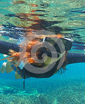 Snorkeling woman in water. Loose hair pretty girl swimming in the sea.