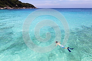 Snorkeller swimming in pristine clear turquoise tropical sea water