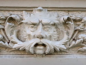 Snot-nosed sculpture of a man`s head on the facade of an old house