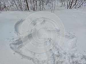 Snow angel design made in deep snow, by lying on back and moving arms up and down, and legs from side to side in winter