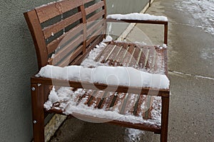 Snow on the arm rests of a city bench after a snow storm