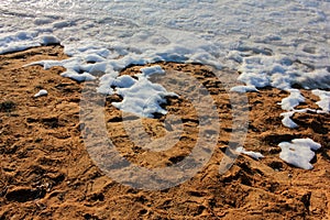 Snow on the beach. Landscape with melting snow on the sand. Sunny spring day. Natural textured background.