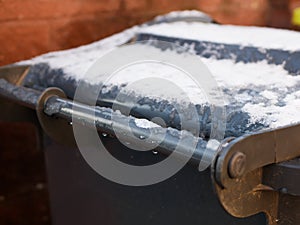 Snow on the bin. gray trash can in a row with snow on top on a cold winter day. Snow Thaw. Thaw