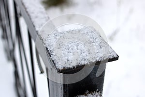 Snow on the black wrought iron railing