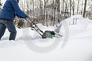 Snow blower in action clearing a residential driveway after snow storm