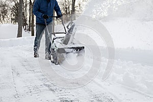 Snow blower in action clearing a residential driveway after snow storm