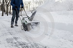 Snow blower in action clearing a residential driveway after snow storm