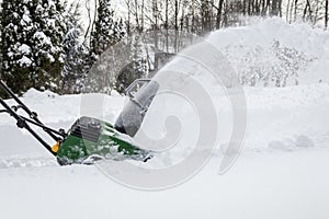 Snow blower in action clearing a residential driveway after snow storm