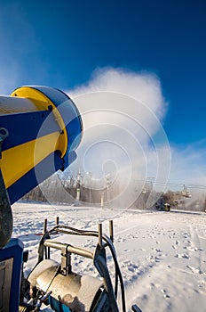Snow cannon in action on the edge of an alpine ski slope