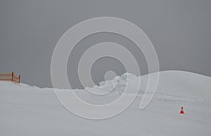 A snow cannon snowed a giant pile of snow. it has a plastic fence and a cone used on the roads. horizon snowboard jump