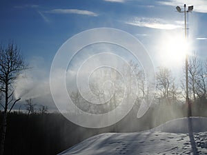 Snow cannon. Snowmaker in action at ski resort spraying artificial snow with mountains in background. Snow that is reflected in