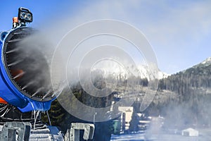 Snow cannon in winter mountains. Snow-gun spraying artificial ice crystals. Machine making snow.