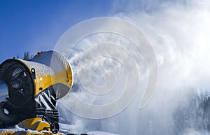 Snow cannon in winter mountains. Snow-gun spraying artificial ice crystals. Machine making snow.