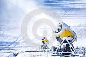 Snow cannon in winter mountains. Snow-gun spraying artificial ice crystals. Machine making snow.