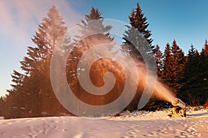 Snow cannon in winter mountains. Snow-gun spraying artificial ice crystals. Machine making snow