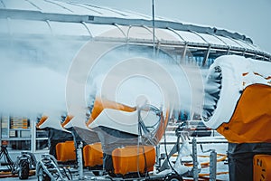 Snow cannons spray artificial snow crystals. Production of artificial snow. Cars make snow.