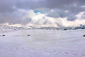 Snow cap mountains with dark cloudy sky at day from flat angle