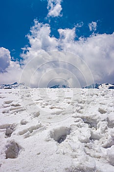 Snow cap mountains with footmarks and bright blue sly