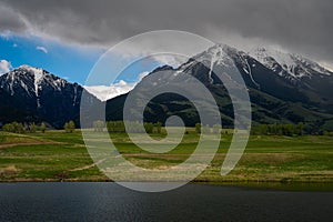 Snow capped Absaroka mountains with a lush green field and lake near Pray, Montana photo