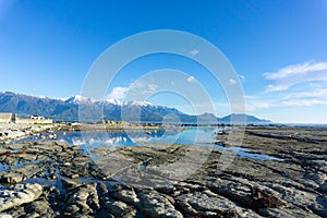 Snow-capped Kaikoura Mountains reflected in calm rockpool