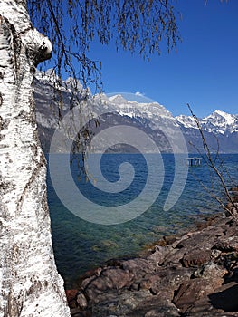 The snow-capped mountain range at the deep blue clear alpine lake: SPRING START.