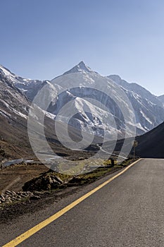 Snow capped mountain and road in Pakistan vertical photo