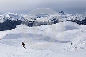 Snow capped mountain vista of Black Tusk and skiers on Whistler, BC.