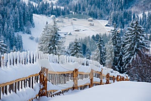 Snow-capped mountains in corpses, snow falls on trees, small village