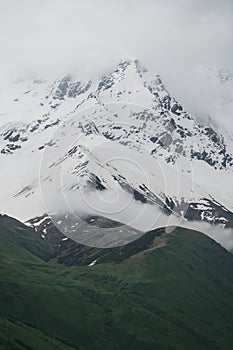 Snow capped mountains, and green mountain ridge in clouds, Georgia