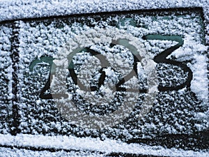 Snow on the car where the numbers are written 2023. New Year concept