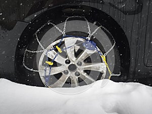 Snow chain on car tyre in snow