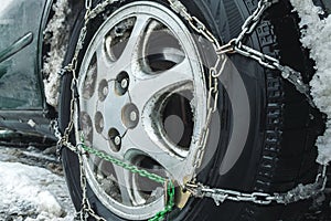 Snow chains on a car wheel. Close-up. A car wheel dressed in chains. Safety on winter snowy roads.