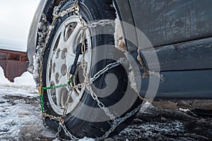 Snow chains on a car wheel in winter. Bottom perspective. The concept of safety on snowy roads.