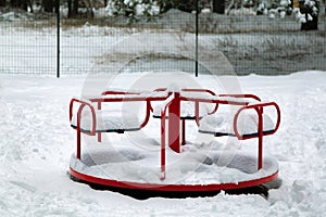 Snow on a children`s swing after a heavy snowfall. swing carousel. Urban scene of city life in winter in a snow storm