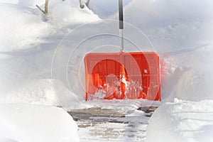 Snow cleaning concept. Red, orange shovel and snow during snowstorm. City ervice cleaning snow winter with shovel after