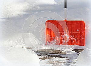 Snow cleaning concept. Red, orange shovel and snow during snowstorm. City ervice cleaning snow winter with shovel after