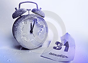 Snow-covered alarm clock and crumpled sheet of tear-off calendar