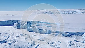 Snow covered antarctic surface aerial view flight.