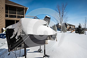 Snow covered BBQ smoker grill in the backyard in winter