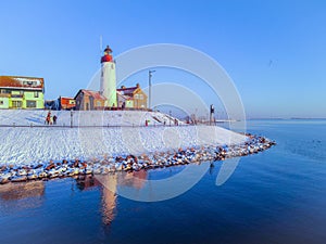 snow covered beach during wnter by Urk lighthouse in the Netherlands photo