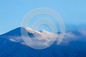 Snow covered beautiful mountain peaks and soft white clouds on b