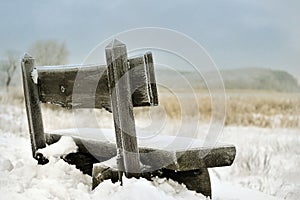 Snow covered bench on coast