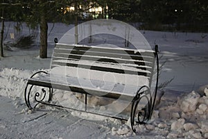 Snow-covered bench in the evening park