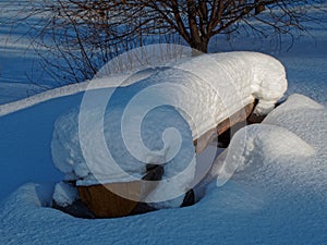 Snow-covered bench lit by sunlight